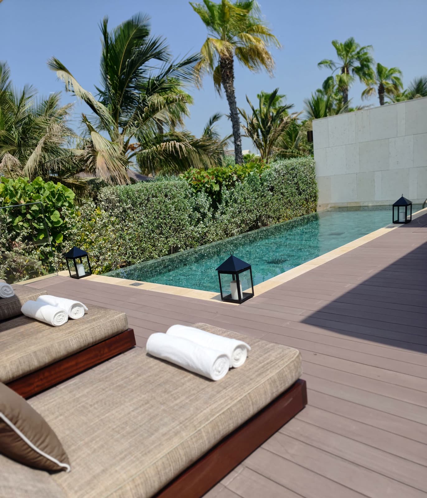 Privater Pool mit Laternen und Liegen zwischen Palmen